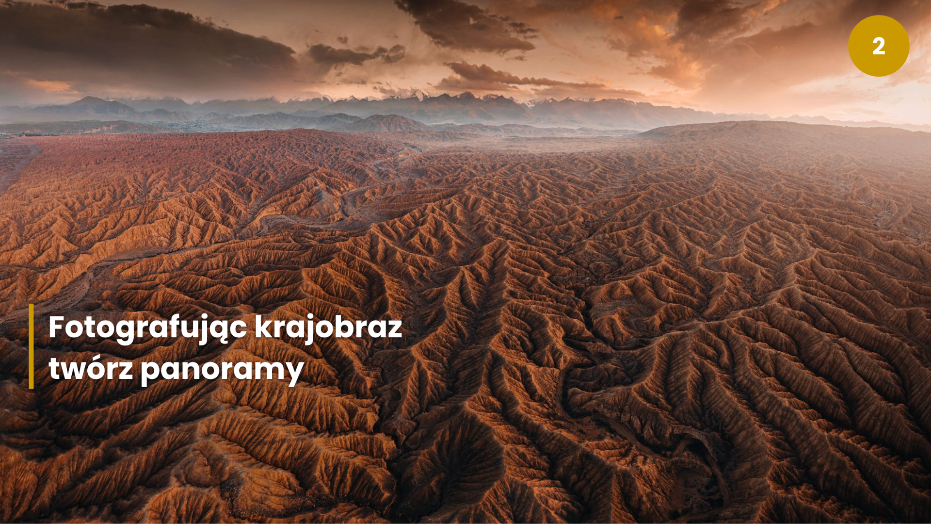 Rozległa, panoramiczna fotografia pofałdowanego pustynnego krajobrazu o zachodzie słońca z górami na horyzoncie — przykład siły kadru panoramicznego w fotografii krajobrazowej